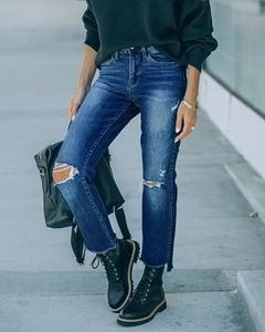 Detailopname van een high-waist jeans met distressed details en gescheurde knieën