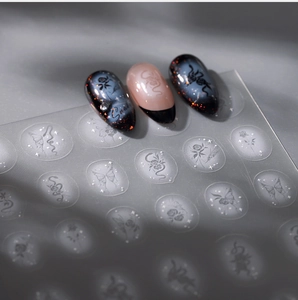 Macro detail of snake and floral nail stickers on dark gradient manicured nails