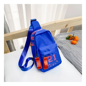 Gros plan d'un sac de poitrine bleu pour enfants avec impression de lettres roses sur un lit