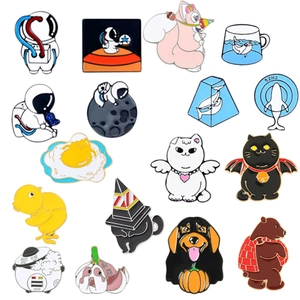 Flat lay of diverse enamel pins featuring cute animals, food, and astronaut designs