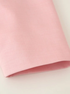 Dettaglio ravvicinato della trama del tessuto rosa e cuciture sulla manica del blazer