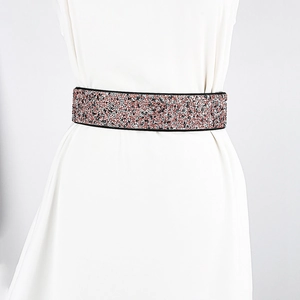 Close-up of a wide elastic belt featuring dense pink and silver rhinestones on a white dress