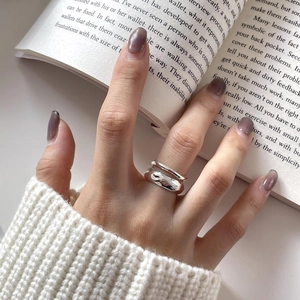 Close-up of irregular textured double silver ring on hand over an open book