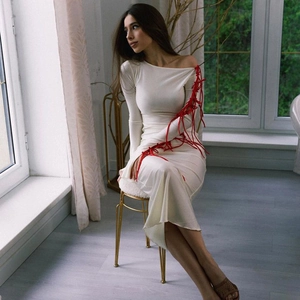 Detail of white long sleeve dress with red lace-up ribbons on sleeves and side slit design