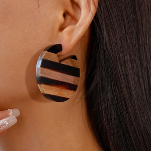 Vintage round geometric resin wood stud earrings with striped design worn by a model