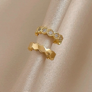 Close-up of gold C-shaped ear cuffs with zircon hexagon and geometric texture on silk