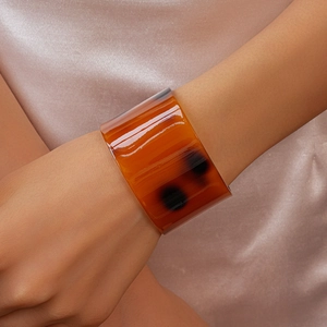 Detailed close-up of a wide tortoiseshell acetate cuff bracelet on elegant satin background