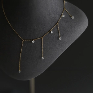 Close-up of gold tassel necklace with zircon charms on a professional display