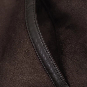Macro detail of dark brown suede fabric with premium leather piping and fine stitching texture