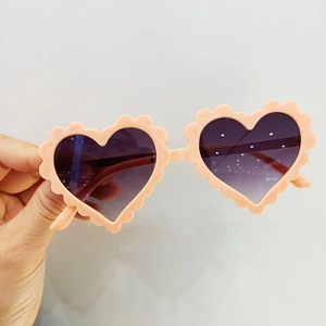 Détail de lunettes de soleil roses en forme de cœur avec bords festonnés et verres