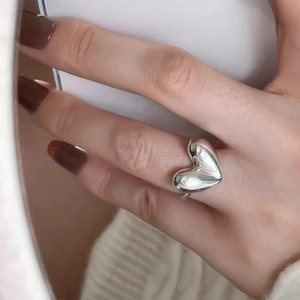 Close-up of a vintage S925 sterling silver heart ring worn on a finger in soft lighting