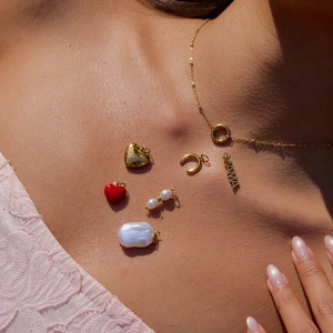Detailed close-up of MAMA and LOVE gold charms with pearls on a stainless steel necklace