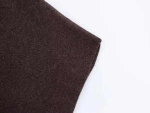 Détail du tissu en maille marron foncé avec texture laine et bords cousus nets