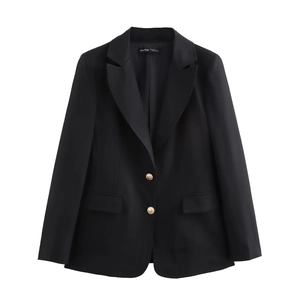 Detailed view of golden metallic buttons on a slim black blazer with textured fabric