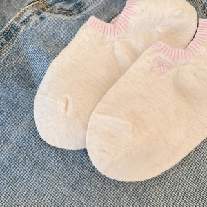 Detail of thin cotton low cut socks with pink bow embroidery and ribbed cuff on denim