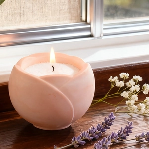Pink tulip candle in resin mold on a wooden windowsill with warm glowing wick