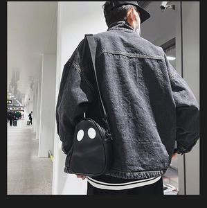 Street style shot of a black ghost-shaped PU crossbody bag worn on a model back