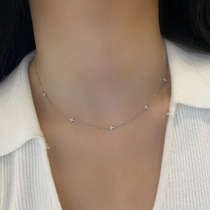 Detailed close-up of a silver flower necklace with zircon pendants on a model neck