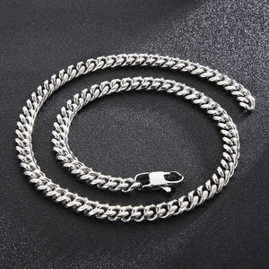 Close-up of polished silver Cuban link chain with lobster clasp on black leather