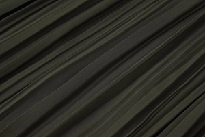 Détail macro de la texture du tissu plissé vert olive de cette robe midi