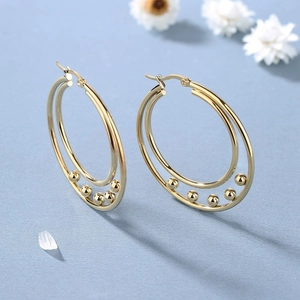 Chic double hoop gold earrings with sliding beads on a premium blue background