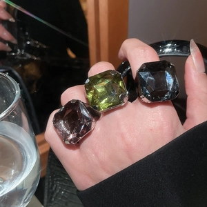 Close-up of three large square-cut crystal rings in purple, green, and grey finishes
