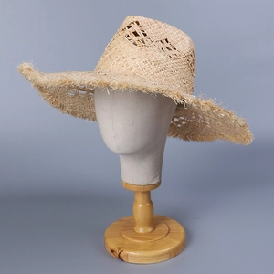 Detail of wide brim straw sun hat featuring hollow weave and frayed edges