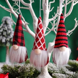 Three assorted Christmas gnomes with knitted hats hanging on a pine tree branch