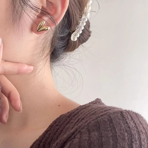 Minimalist gold heart-shaped stud earrings with geometric 3D fold design worn by a model