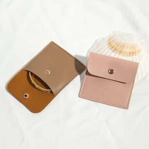 Flat lay of pink and brown PU leather jewelry pouches with golden snap button and shell