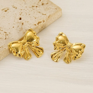 Detailed macro view of 18k gold plated bow stud earrings on a natural stone background