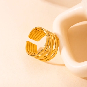 Anillo de acero de titanio dorado tejido sobre un fondo minimalista de cerámica