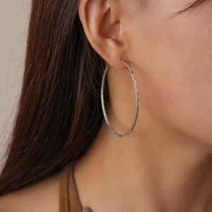 Close-up of matte silver hoop earring with frosted texture shown on a female model
