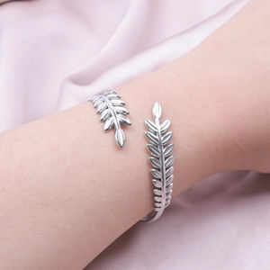 Detail of adjustable C-shaped silver leaf wheat pattern bangle with polished metallic finish