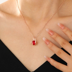 Detail of rose gold gothic necklace with red heart gemstone worn by a model