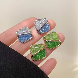 Close-up of geometric square earrings with gradient blue and green crystal stones