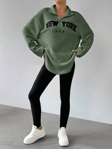 Détail du sweat-shirt oversize en polaire vert sauge avec broderie New York et col zippé