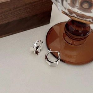 Polished silver U-shaped twisted hoop earrings on a textured minimalist background