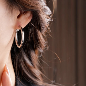 Close-up of minimalist silver hoop earring on model showing smooth metallic luster