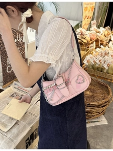 Close-up of pink Y2K baguette bag with silver chains, buckles and star studs