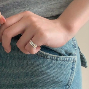 Detailed view of silver S925 heart embossed ring worn by a model on denim fabric