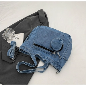 Detailed flat lay of blue denim tote bag with mini round coin purse and silver hardware