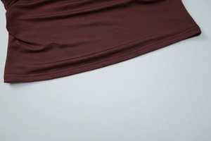 Close-up of double-stitched hem on dark brown sleeveless top fabric texture