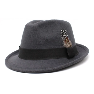 Detail of dark grey wool fedora featuring a black grosgrain band and natural feather accent