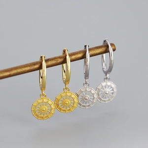 Detail of silver and gold geometric sun totem hoop earrings on a display stand