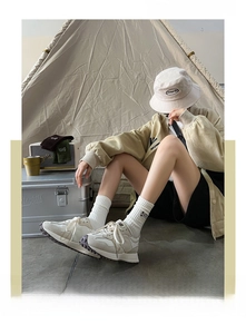 Detail of white cotton crew socks with camping oil lamp embroidery in outdoor setting