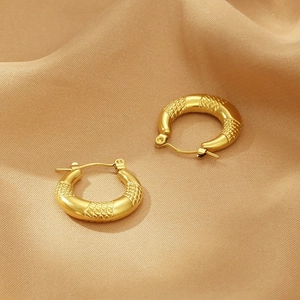 Detailed macro view of gold U-shaped hoop earrings with unique snakeskin scale texture