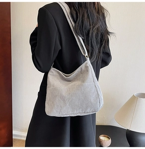 Side view of a grey corduroy tote bag with external pocket worn by a model in soft light