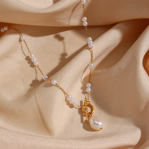 Baroque pearl necklace with gold chain, OT toggle clasp on beige silk fabric background