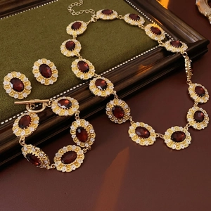 Vintage gold jewelry set with oval red gems and floral details on green velvet tray